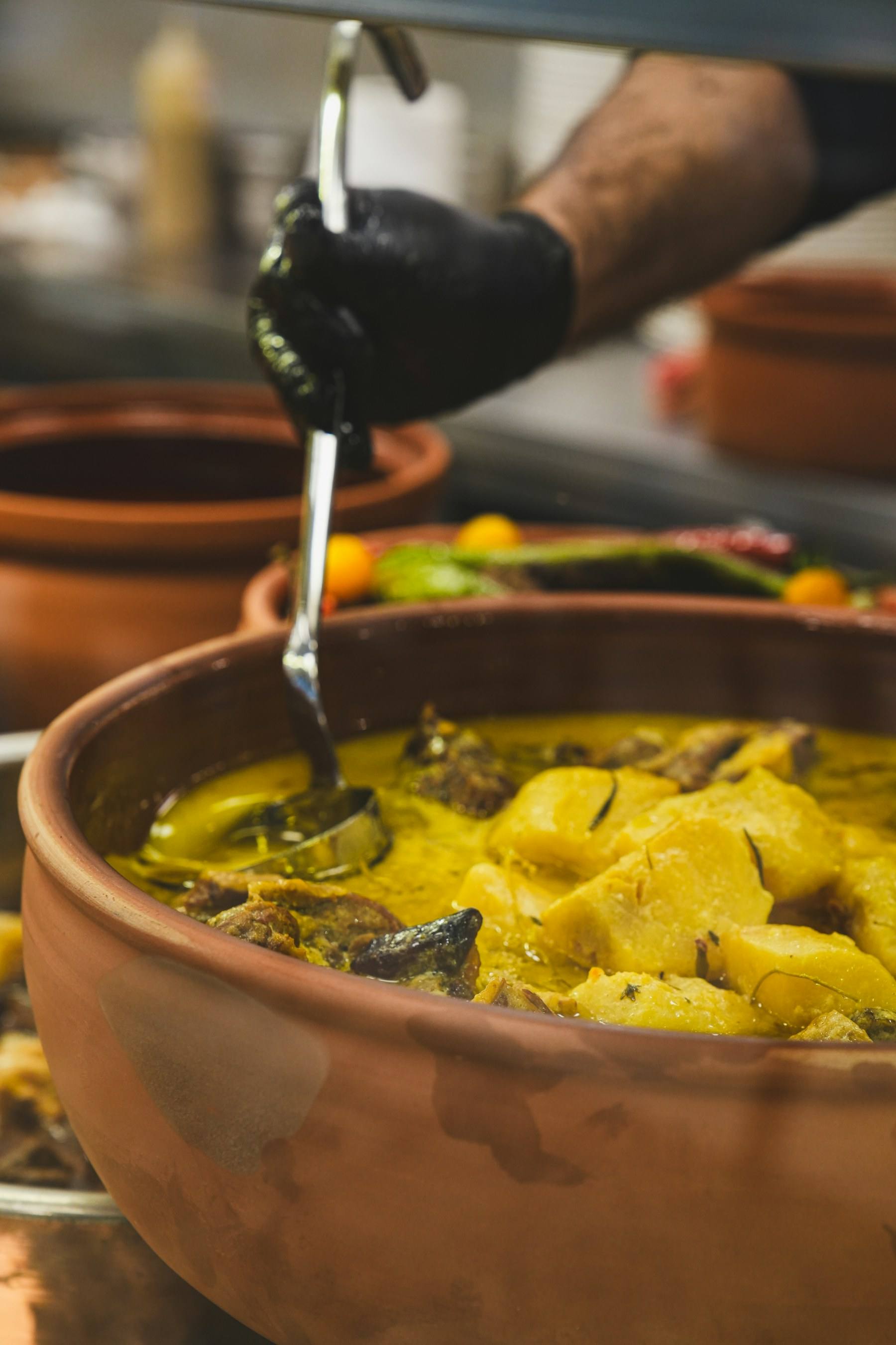 Curry ladled from a large clay pot