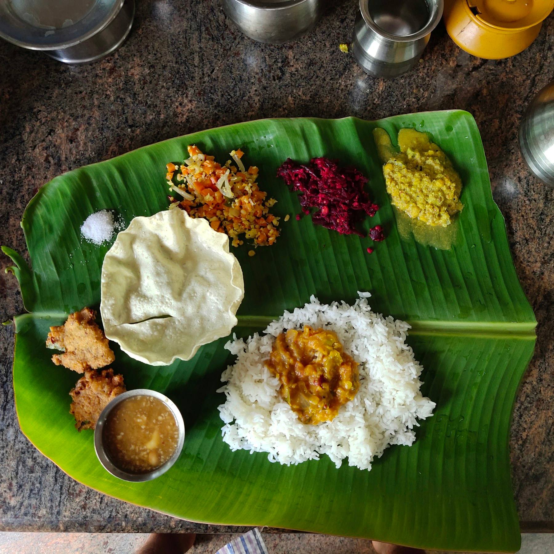 A vegetarian sadya laid out on a banana leaf, seen from above