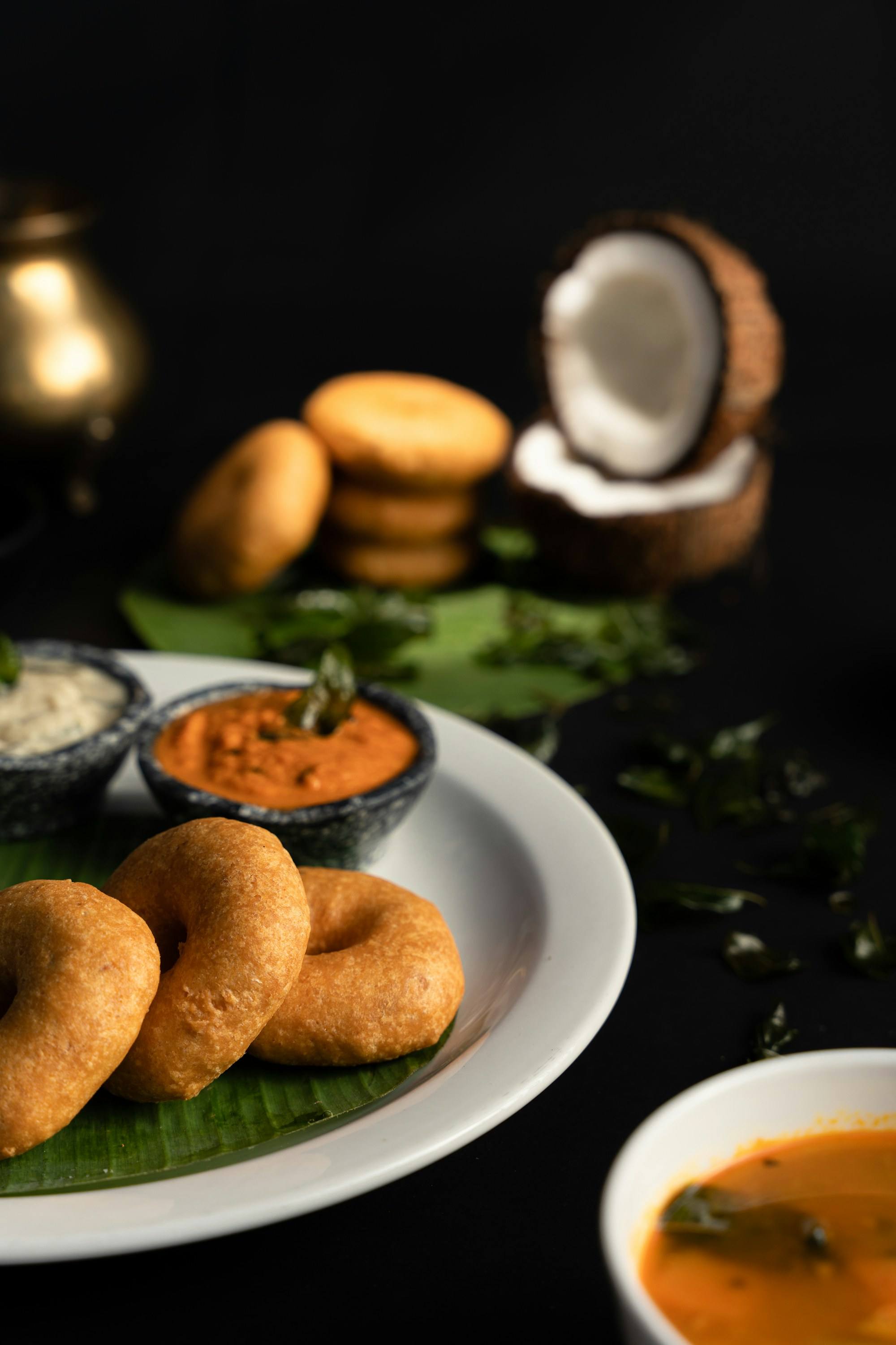 Crisp lentil vada beside a split coconut and chutney
